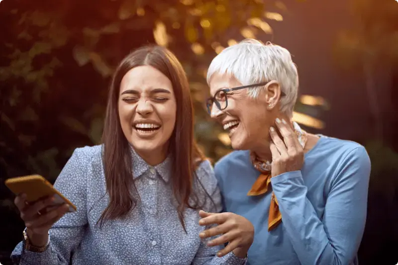 Vrouw en dochter lachend met telefoon in handen