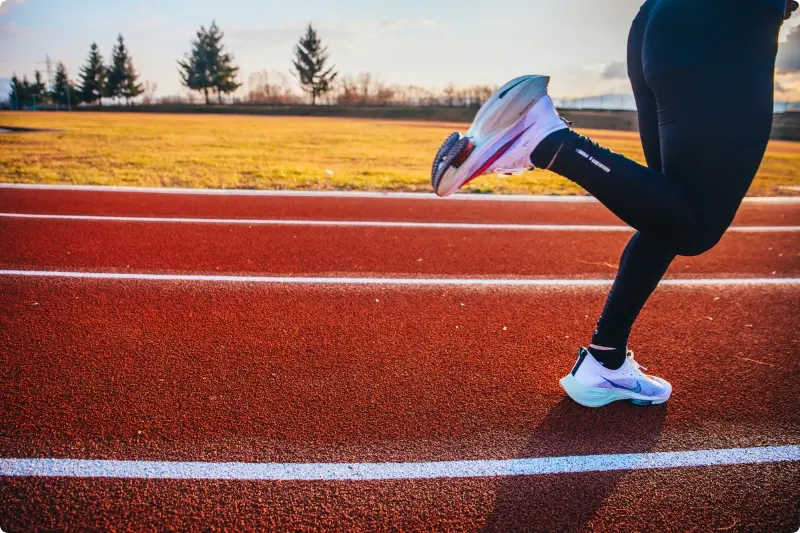 Twee benen rennend op een atletiekbaan, passend bij de vraag of het tijd is voor een pas op de plaats bij beleggen tijdens beursrecords.