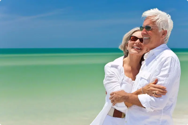 Ouder stel lachend op een strand want beleggen voor hun pensioen