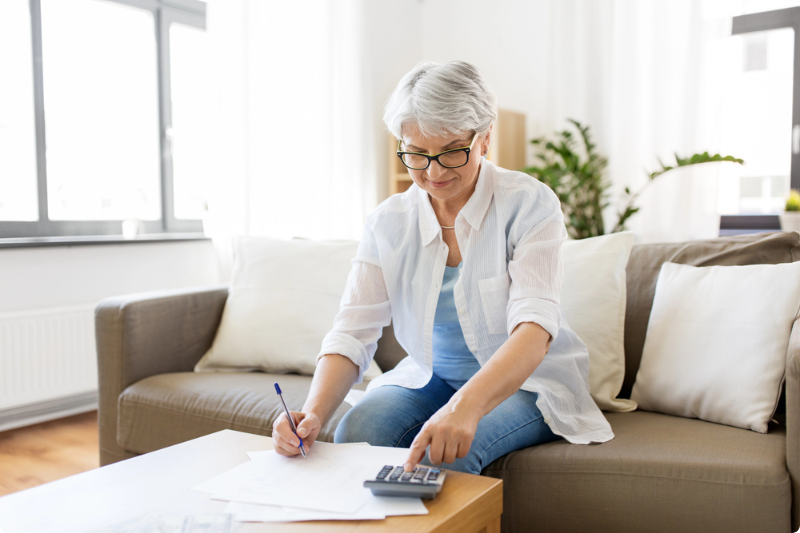 Vrouw op de bank met pen en rekenmachine