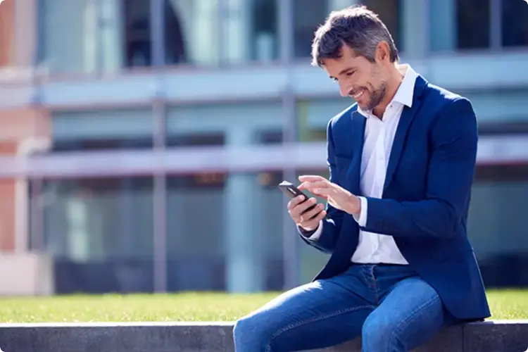 Man kijkt blij naar zijn telefoon want hij heeft een lange beleggingshorizon