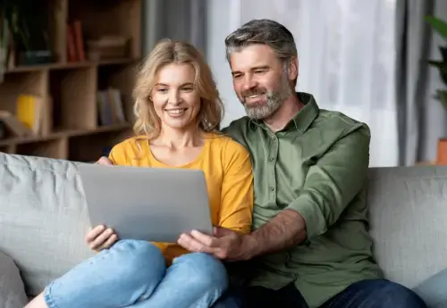 Man en vrouw kijken blij naar tablet waar zij hun Care IS beleggingen op volgen